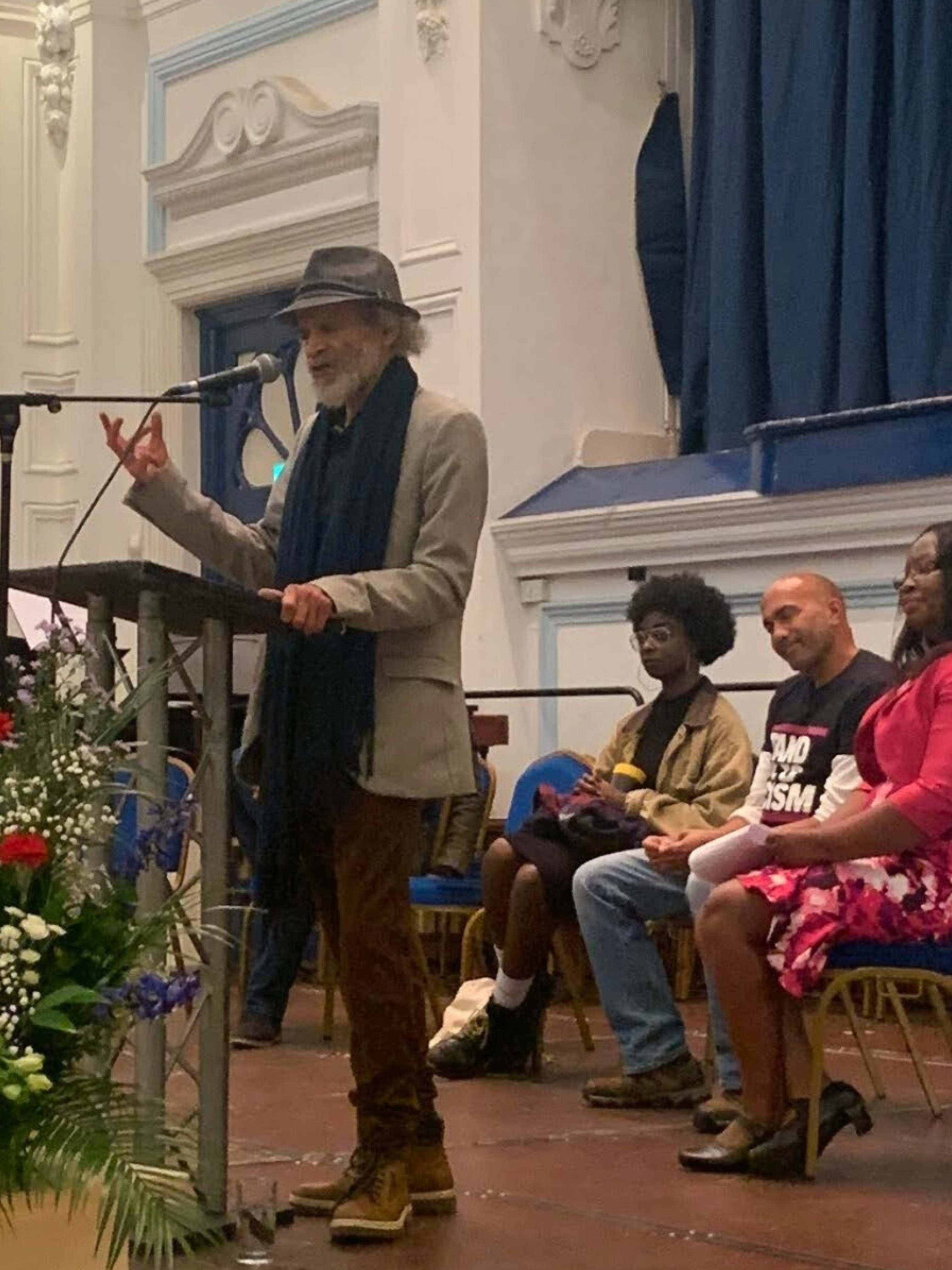 John Agard reading poetry with Priss Nash, Nick Hines and Cllr Dr Janet Baah behind